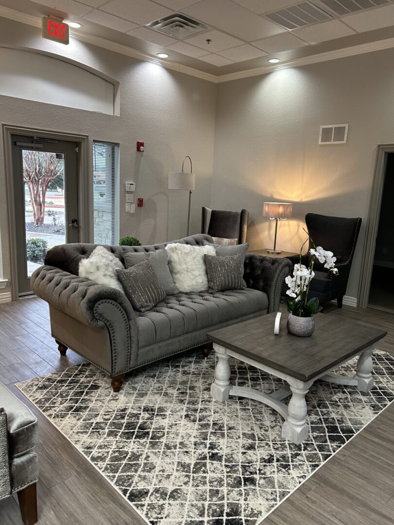 A living room with gray furniture and a white rug.